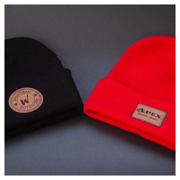 Knit red and black winter hats with sewn on faux leather patch logos by Apex Transfers